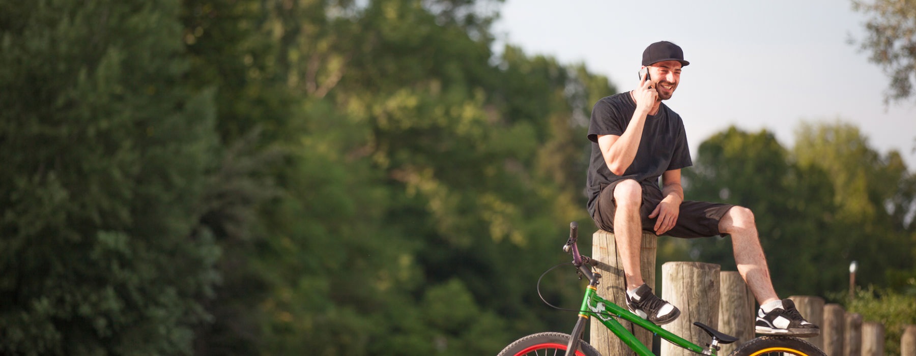 man on a cell sits on posts next to his bicycle